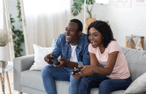 Cheery african american couple playing video games at home