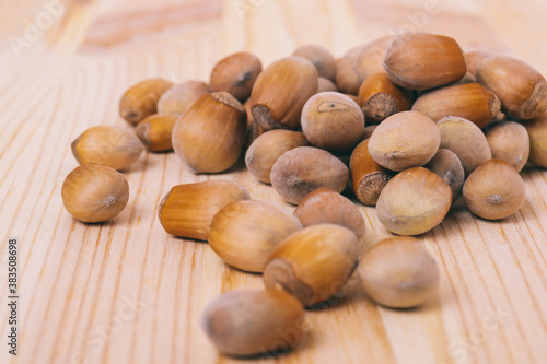 Pile of nuts. Hazelnuts. Whole nuts. Corylus avellana. Macro photo, close up, on wooden table.