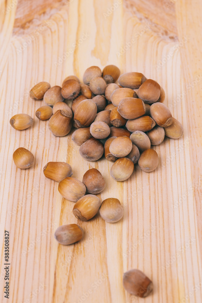 Pile of nuts. Hazelnuts. Whole nuts. Corylus avellana. Macro photo, close up, on wooden table. Pile of nuts. Hazelnuts. Whole nuts. Corylus avellana. Macro photo, close up, on wooden table.