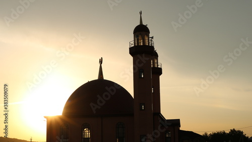 silhouette of a mosque against the background of a sunset sky in the rays of the setting sun photo