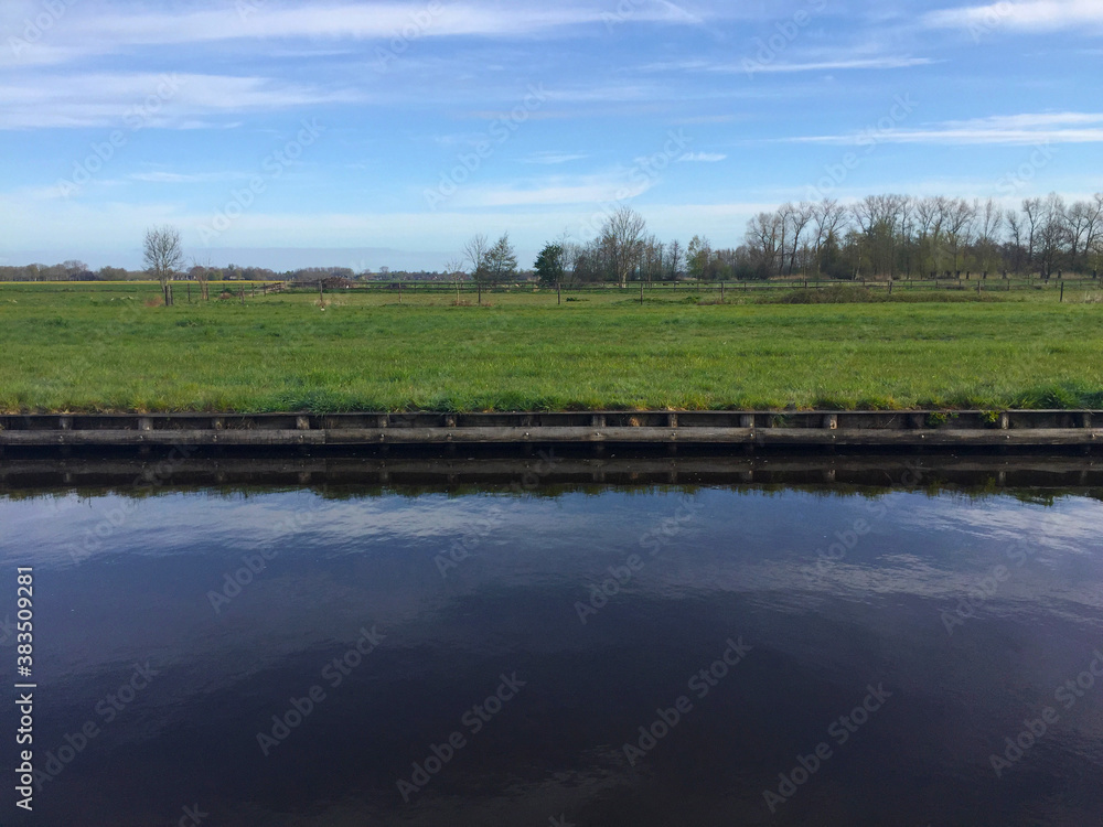 the river near meadow against blue sky in the village of Giethoorn, Holland Netherlands the river near meadow against blue sky in the village of Giethoorn, Holland Netherlands
