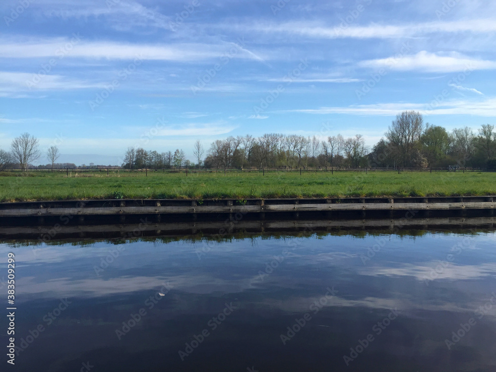 the river near meadow against blue sky in the village of Giethoorn, Holland Netherlands