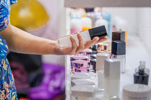 Woman comparing cosmetic plastic bottle with dispenser pump on shelf. Cosmetics Packages design Beauty Products.