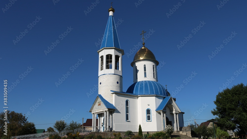 Gaverdovsky, Maykop, Republic of Adygea / Russia - October 10, 2020: Orthodox white temple with gilded domes on a clear sunny day against the background of a bright blue sky