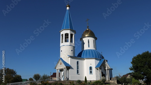 Gaverdovsky, Maykop, Republic of Adygea / Russia - October 10, 2020: Orthodox white temple with gilded domes on a clear sunny day against the background of a bright blue sky