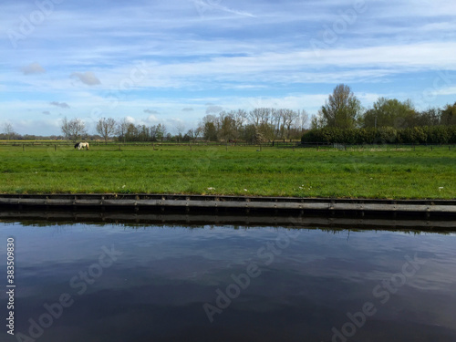 the river near meadow against blue sky in the village of Giethoorn, Holland Netherlands