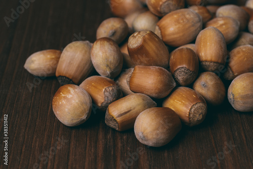 Pile of nuts. Whole nuts. Hazelnuts. Corylus avellana. Macro photo, close up, on dark wooden background.