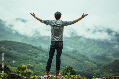 A man raising his hands with a relaxed pose at the forest in the rainy season.