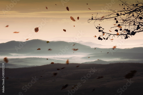 fantasy autumn landscape with falling leaves and hills at sunset © andreiuc88