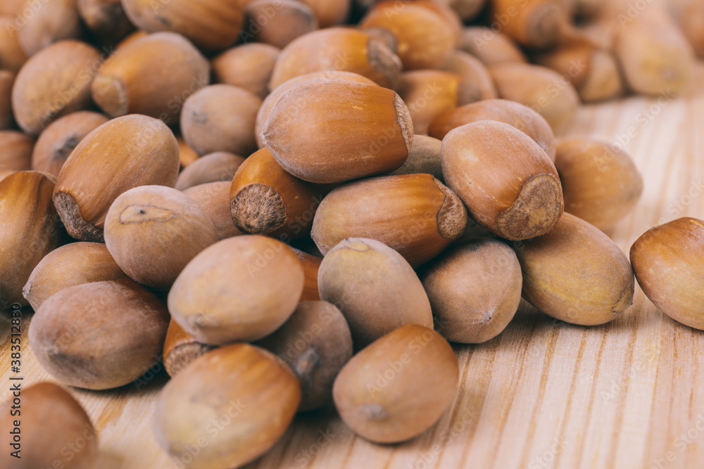 Pile of nuts. Hazelnuts. Whole nuts. Corylus avellana. Macro photo, close up, on wooden table. Pile of nuts. Hazelnuts. Whole nuts. Corylus avellana. Macro photo, close up, on wooden table.