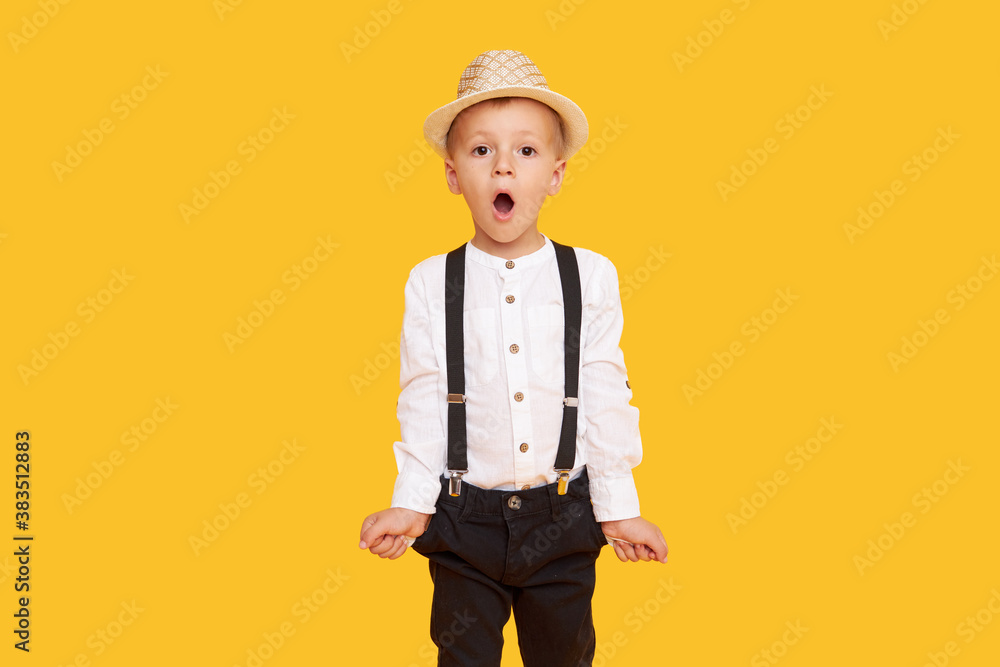 Stylish child boy in trendy black trousers with empty pockets posing on yellow background Stylish child boy in trendy black trousers with empty pockets posing on yellow background