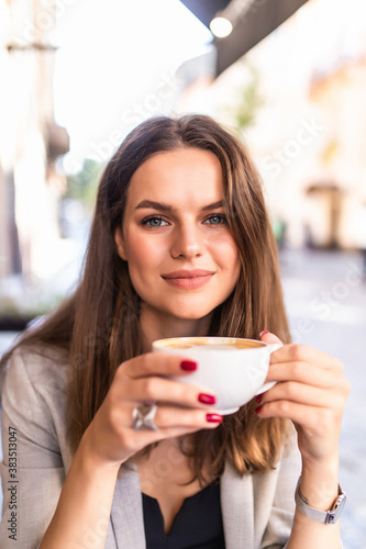 Portrait of a young woman enjoying coffee sitting outdoors at cafe during the morning