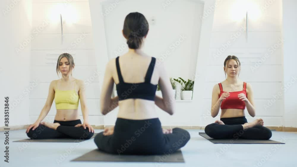 Girls practicing yoga. Yoga instructor with two students in a studio. Instructor facing students. Camera moving left. Girls practicing yoga. Yoga instructor with two students in a studio. Instructor facing students. Camera moving left.