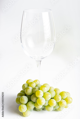 Bunch of ripe and juicy green grapes close-up in wine glass on a white background