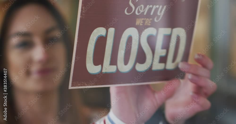 Female hairdresser changing sign board from Closed to Open at hair