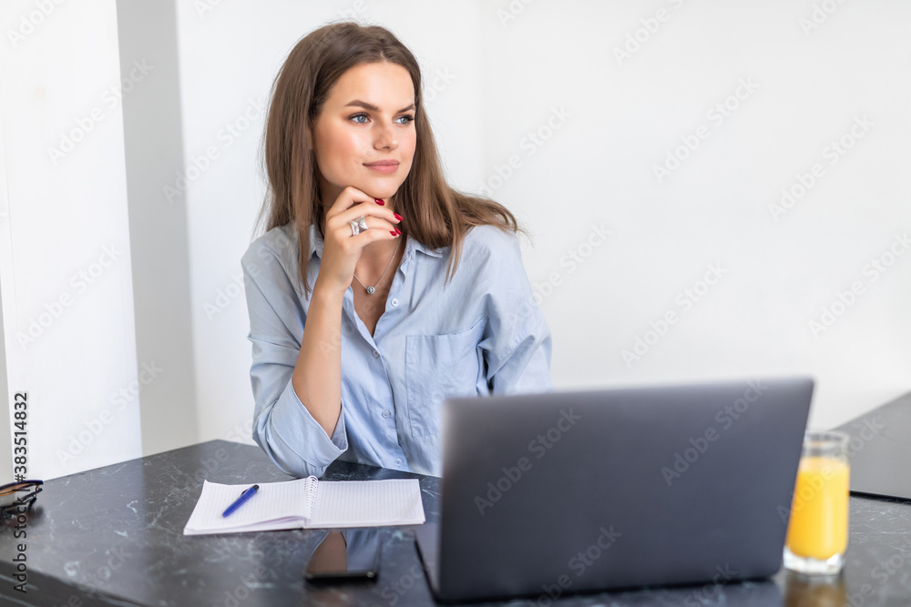 Young woman working from home office. Freelancer using laptop and the Internet workplace in cozy kitchen. Successful female business, self development. Lifestyle moment. Young woman working from home office. Freelancer using laptop and the Internet workplace in cozy kitchen. Successful female business, self development. Lifestyle moment.