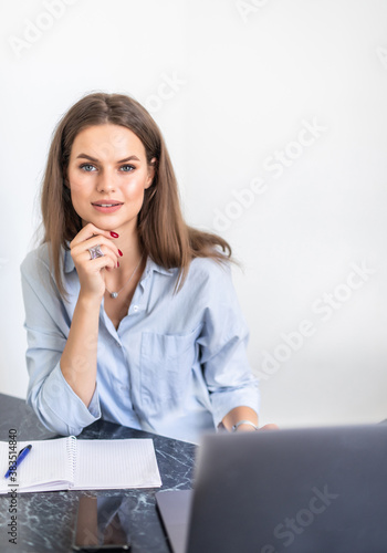 Young woman working from home office. Freelancer using laptop and the Internet workplace in cozy kitchen. Successful female business, self development. Lifestyle moment.