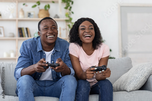 Happy african american couple playing video games at home