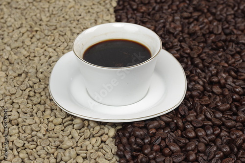Black coffee is served in a glass cup  which is placed on top of the coffee beans which are arranged neatly to form a heart.