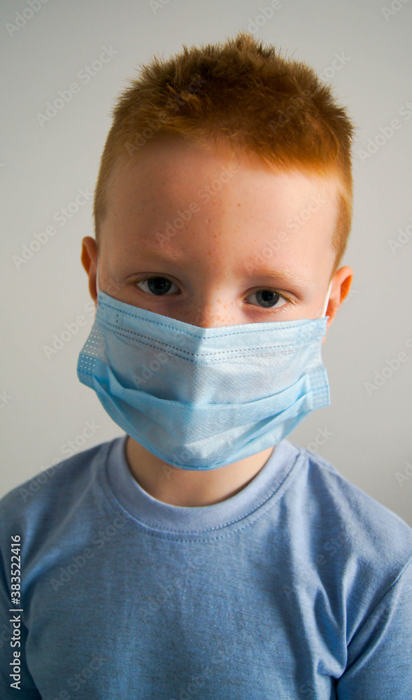 Ginger red head child in a protective mask on the white background. Kid using the medical face mask for protection during the covid-19. Ginger red head child in a protective mask on the white background. Kid using the medical face mask for protection during the covid-19.