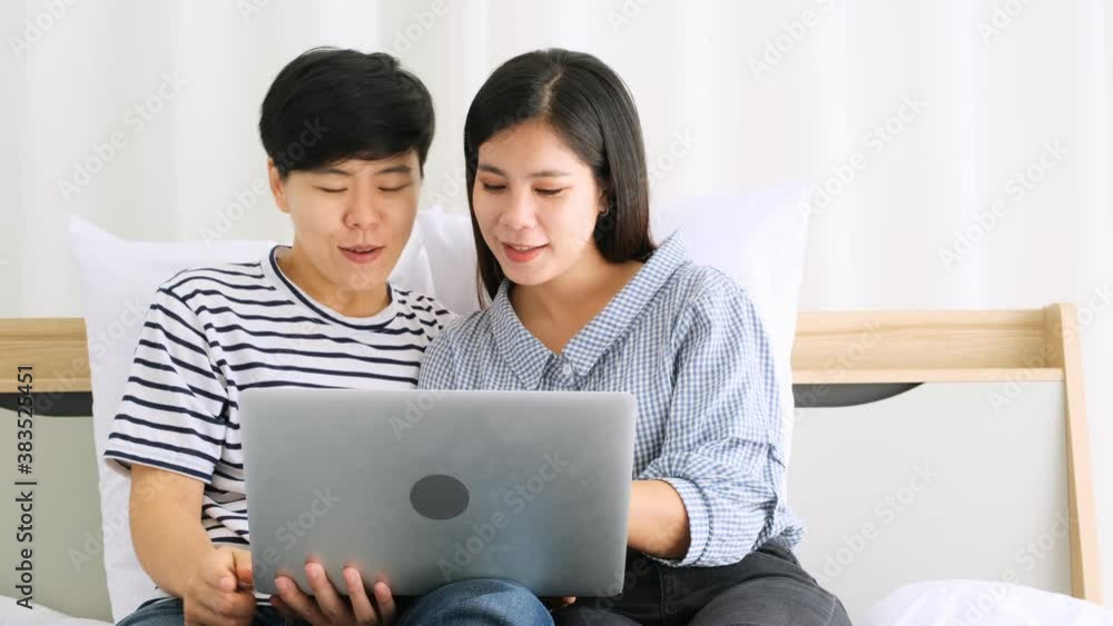 Couple of lesbian women lovers using laptop together on bed with happily in the bedroom. Couple of lesbian women lovers using laptop together on bed with happily in the bedroom.