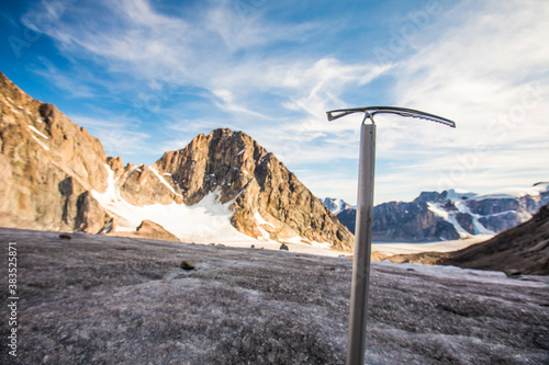 Climbers ice axe in front of glacier and mountains. photo