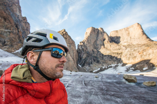 Portrait of climber wearing helmet and sunglasses below mountain summi photo