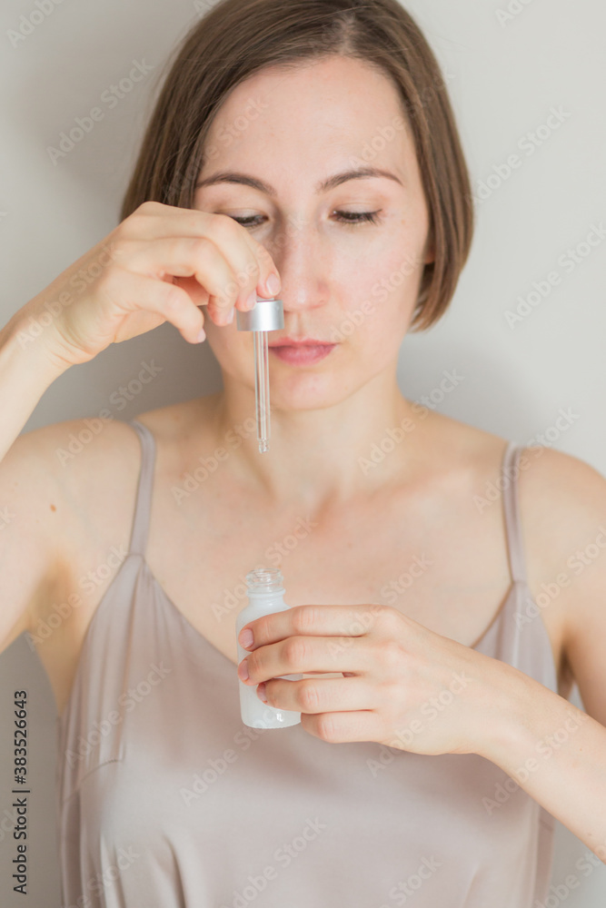 Close up beauty portrait of woman holding bottle of serum Close up beauty portrait of woman holding bottle of serum