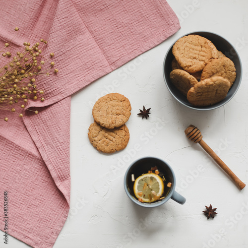 Cup of black tea, lemon, homemade cookies and tablecloth on white rustic background. Breakfast concept. Top view, flat lay style