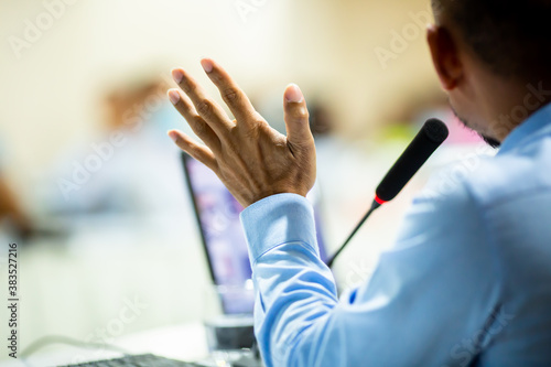 Selective focus to desktop wireless conference microphones with blurry business man in a meeting room, microphone on the desk in meeting room with blurry speaker. The concept of speaking.