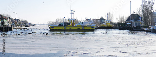 Small roll-on roll-off car ferry crossing a frozen canal in the Netherlands photo