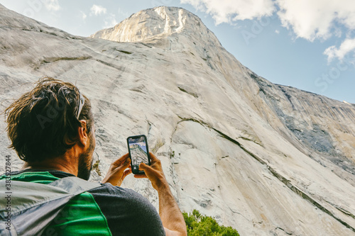 Young man taking picture of El Capitan Mountain in Yosemite Park. photo