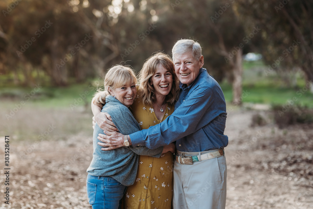 Portrait of Adult Woman and Senior Parents Hugging at Park Portrait of Adult Woman and Senior Parents Hugging at Park