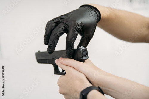 Living in a pandemic. Shooting instructor in gloves showing to the client how to use a gun at a shooting range amid a pandemic