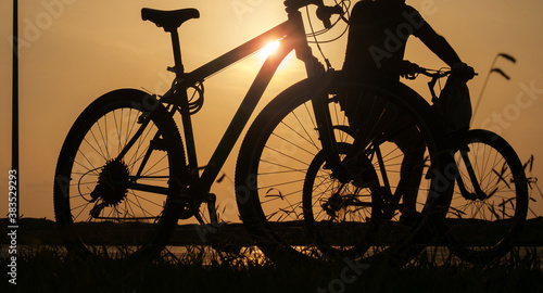 A silhouette of a bike at sunset. The sun shines through the bicycle frame, selective focus