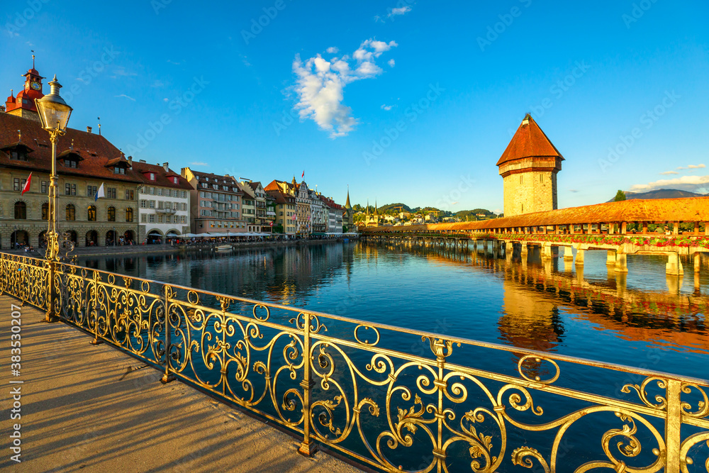 Cityscape of Lucerne on Lake Lucerne, Switzerland at sunset. Historic covered wooden footbridge, Chapel Bridge with Water Tower reflect on Reuss river. Luzern the medieval city of bridges.