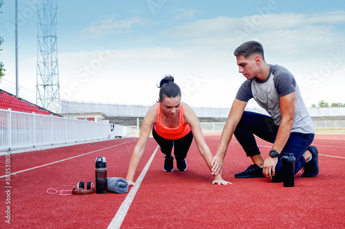 Young man and a young girl are training on the outdoor track