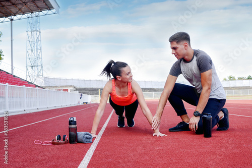 Young man and a young girl are training on the outdoor track