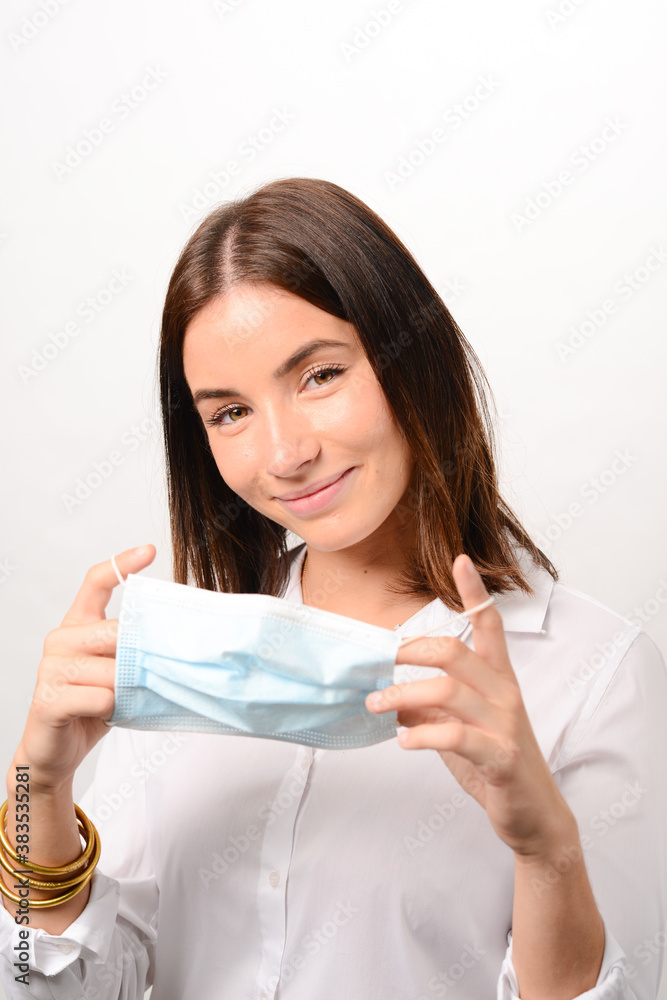young beautiful woman putting on a surgical mask on white background during covid 19 pandemic young beautiful woman putting on a surgical mask on white background during covid 19 pandemic