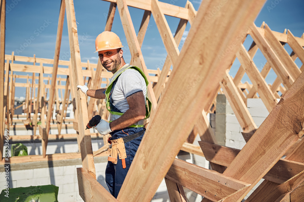Construction worker wearing a helmet and holding a drill Construction worker wearing a helmet and holding a drill