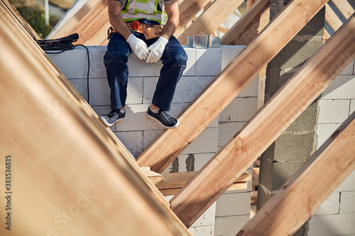 Professional builder having rest while sitting on the wall
