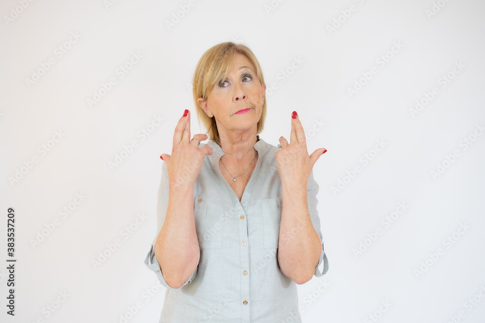Senior woman with blond hair wearing casual blouse gesturing finger crossed smiling with hope. luck and superstitious concept. Senior woman with blond hair wearing casual blouse gesturing finger crossed smiling with hope. luck and superstitious concept.