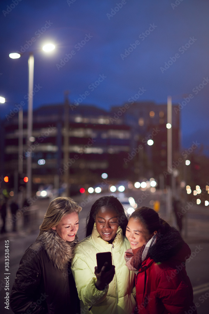 Group Of Female Friends On City Street At Night Ordering Taxi Using Mobile Phone App