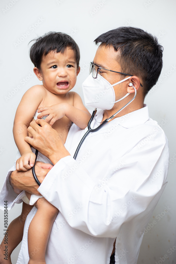 Doctor young man uniform examining a little boy with a stethoscope standing Doctor young man uniform examining a little boy with a stethoscope standing