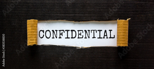 The word 'confidential' appearing behind torn black paper. Business concept. photo