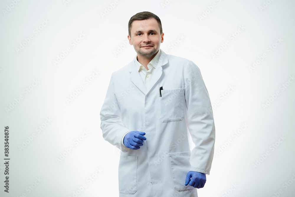 A kind male caucasian doctor in a white lab coat and blue disposable medical gloves is posing with a smile. A scientist is isolated over white background.