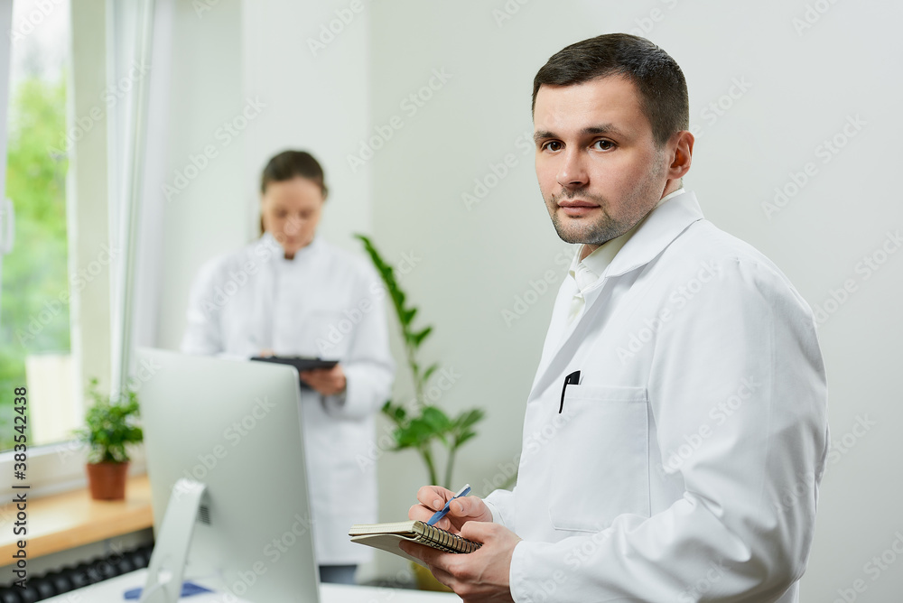 A serious caucasian doctor with a notebook and a pen records the patient’s medical history in a hospital. A female therapist is doing notes in a clipboard near an all in one computer in a clinic. A serious caucasian doctor with a notebook and a pen records the patient’s medical history in a hospital. A female therapist is doing notes in a clipboard near an all in one computer in a clinic.