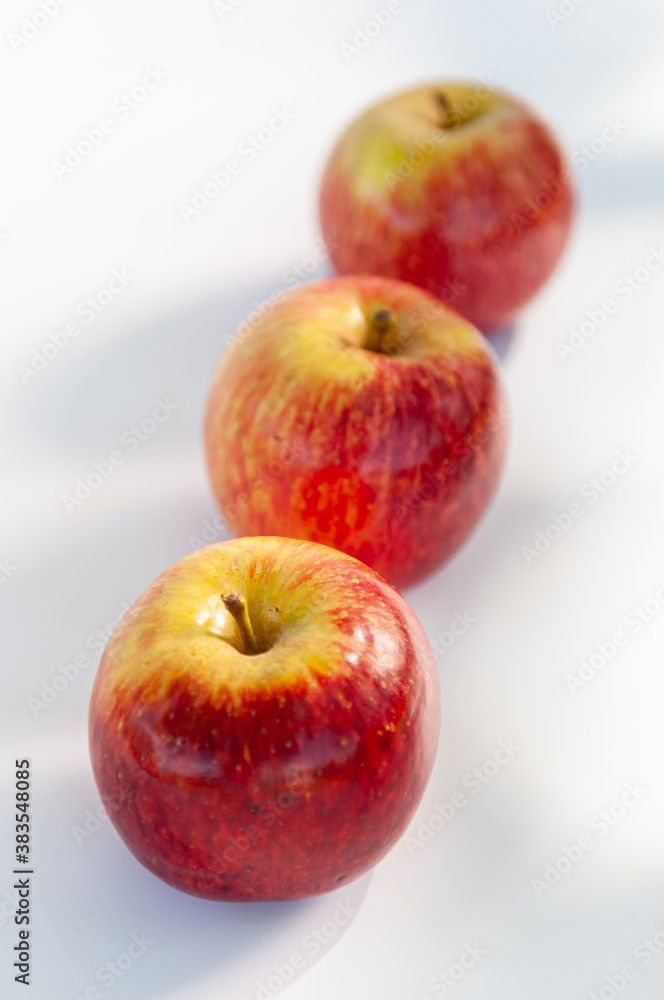 Three red apples with focus on the foreground and blur background on a white table. Selective focus Three red apples with focus on the foreground and blur background on a white table. Selective focus