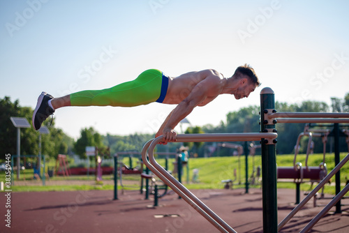 The fit athlete doing exercises at outdoor gym.