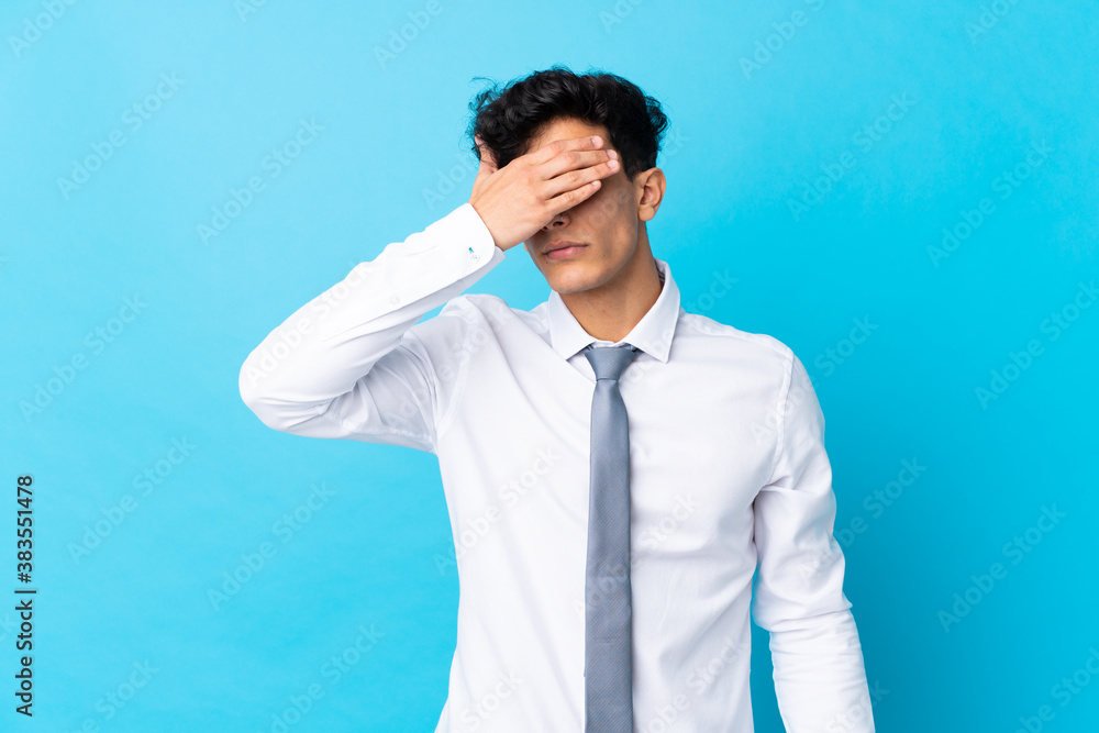 Young Argentinian businessman over isolated blue background covering eyes by hands Young Argentinian businessman over isolated blue background covering eyes by hands